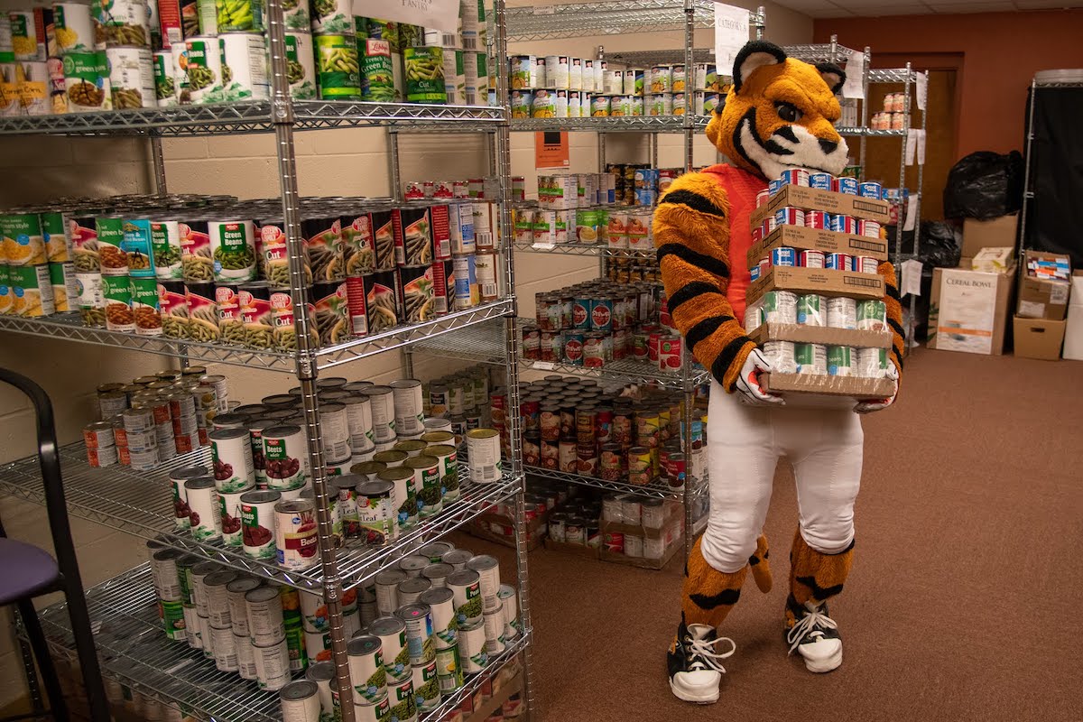 Benny the Bengal holding cases of food in Benny's Pantry.