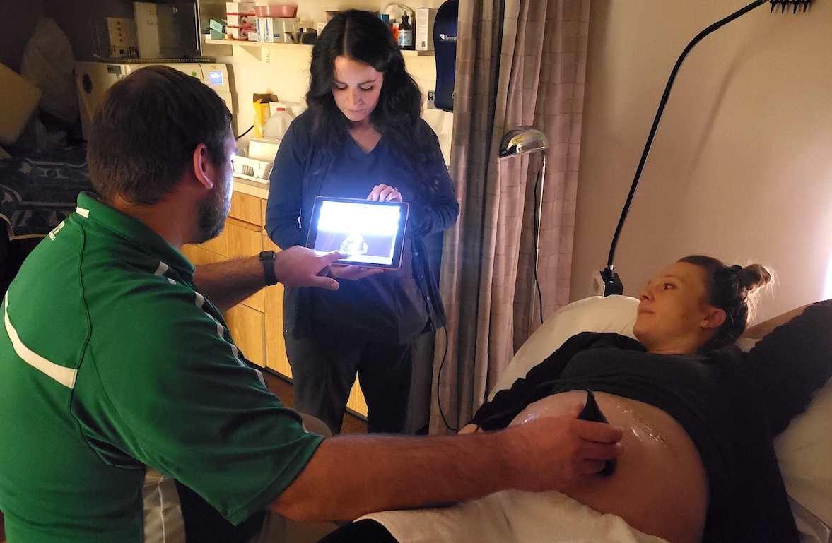 Pregnant woman receiving ultrasound treatment from professor and MD.
