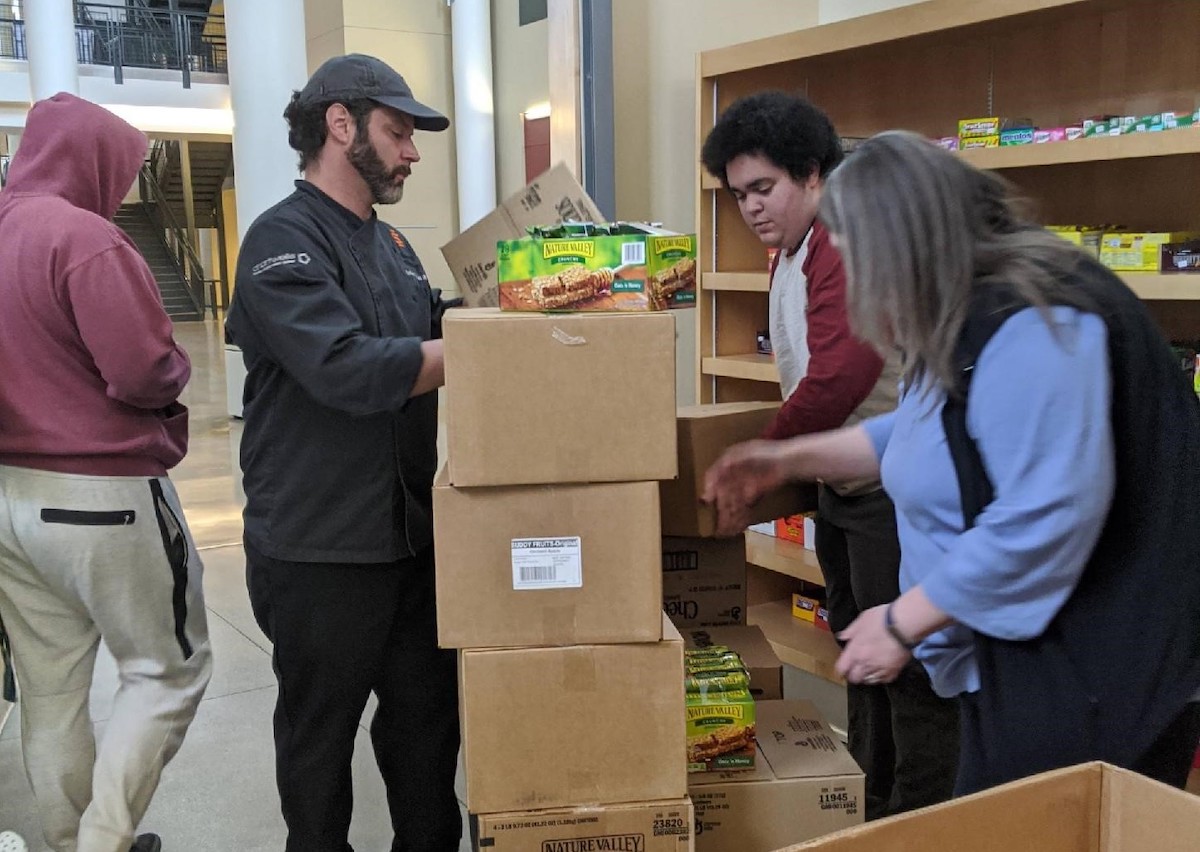 Chartwell employee delivering boxes of food snack packs to Benny's pantry.