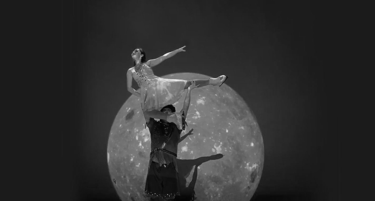 Photo of two skaters on stage with a full moon in background.