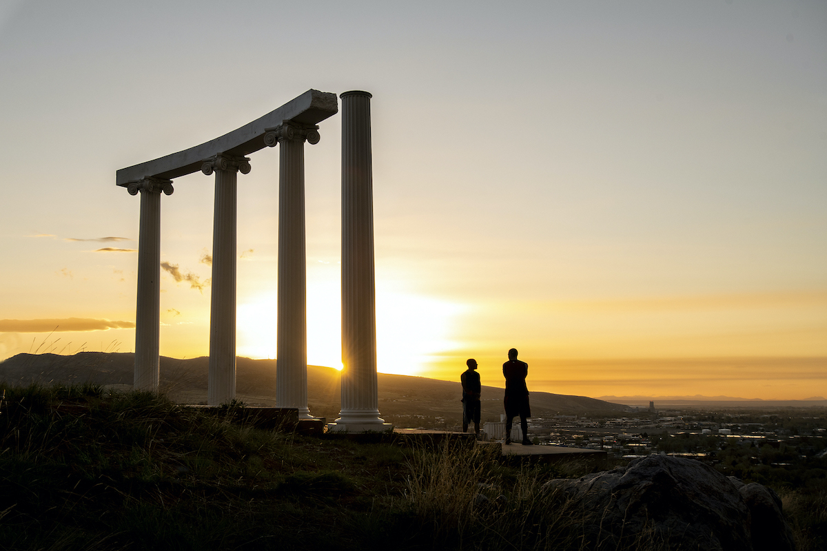 Red Hill Pillars at sunset with the silhouettes of two people standing near by.