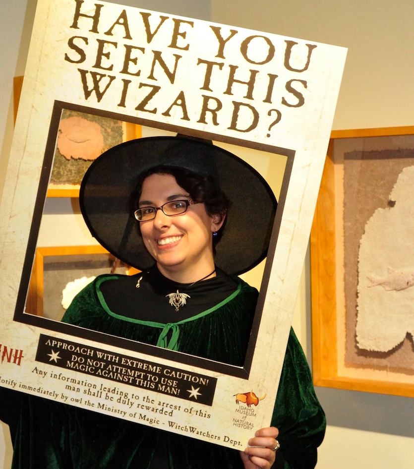 Photo of museum employee dressed as a witch standing in a photo cutout. 