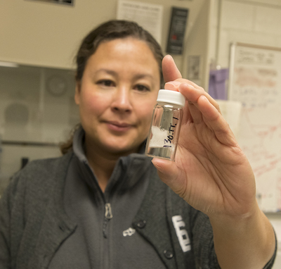 Amy Commodore holding up an owl pellet sample in a small jar that was used in the study.