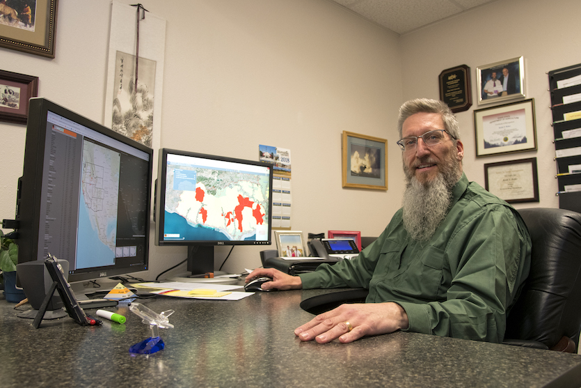 Keith Weber sitting at his desk in front of computer screens.