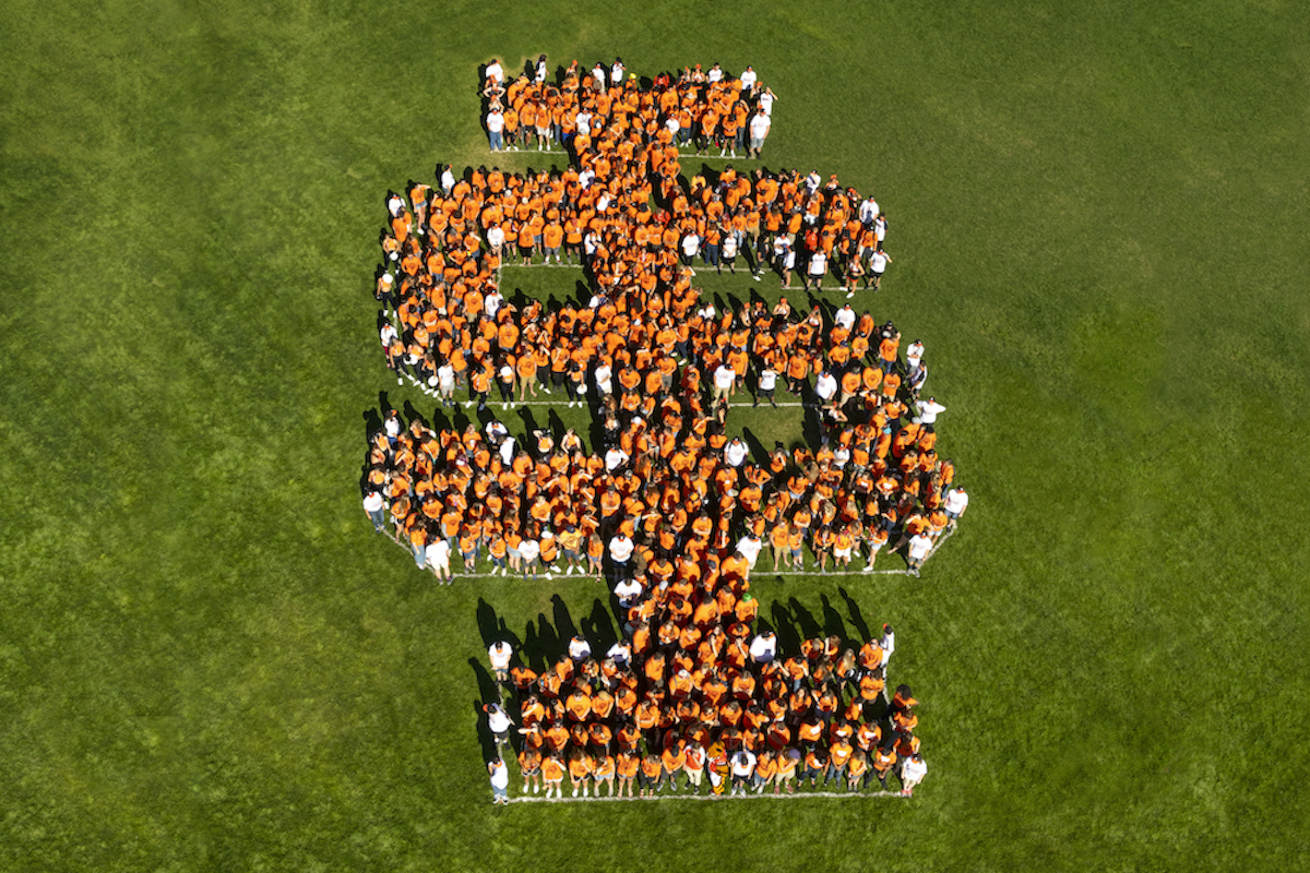 Students forming a giant letter orange 