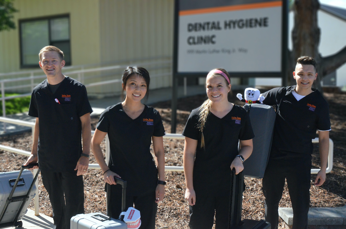 Four dental hygiene students with portable units for providing care.