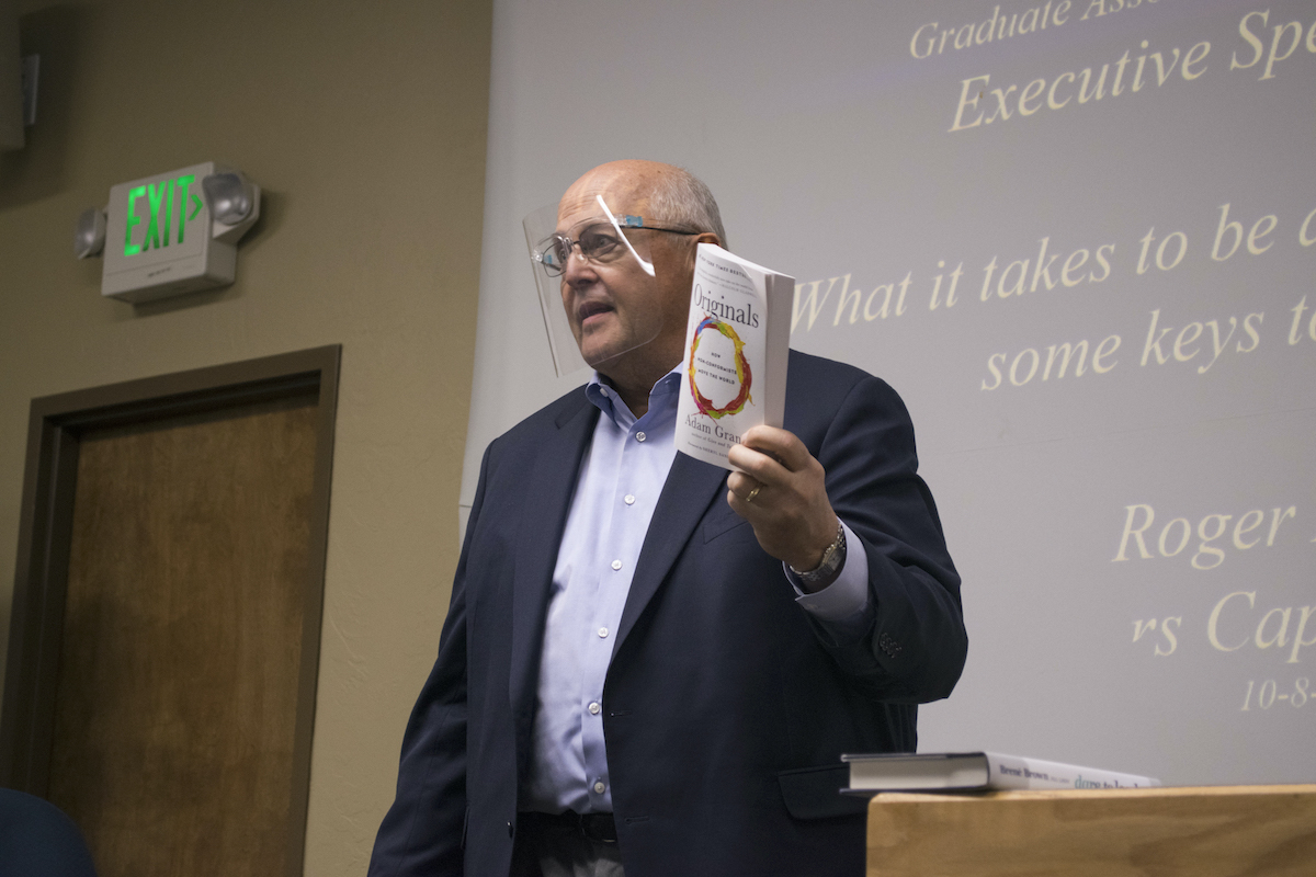 Akers holding a book during a presentation.