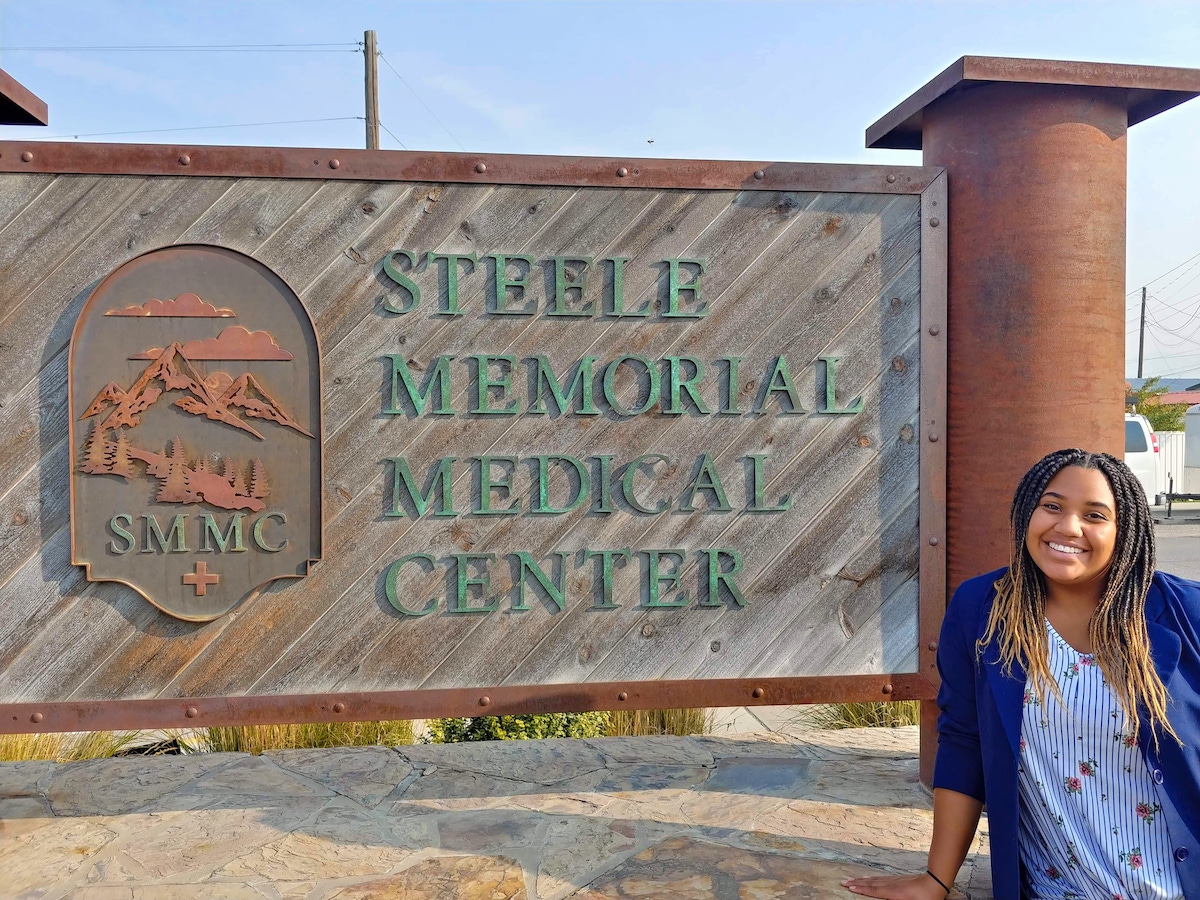 Photo of Maya Tillotson standing by a sign