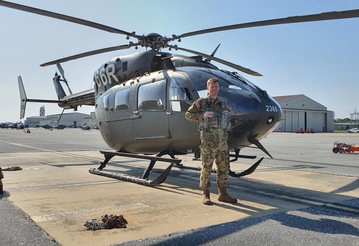 Picture of Mr. Henderson standing in front of a helicopter.