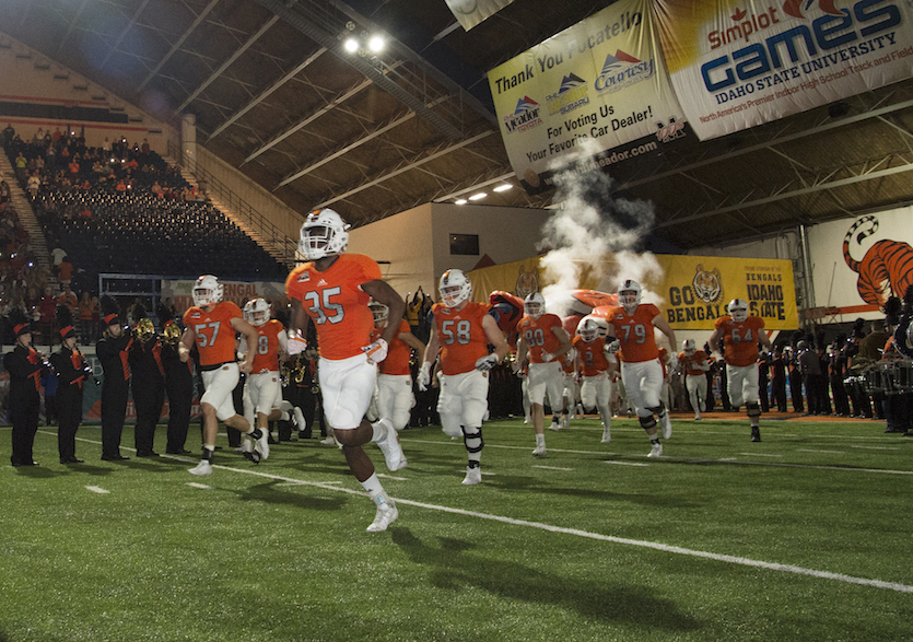 Football players running on the field during 2017 Homecoming game