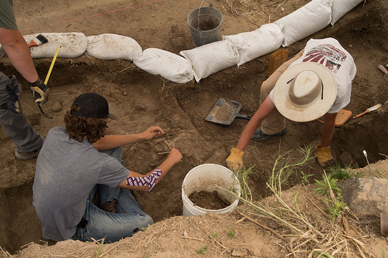 Students carefully digging in trench