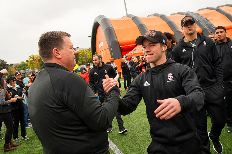 President Satterlee shaking hands with the players before the homecoming game