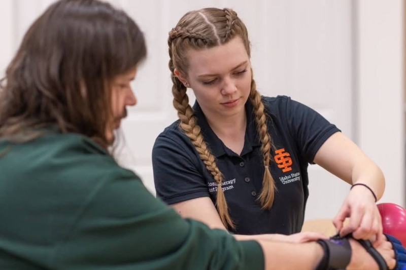 Emma Kolman adjusting a wrist brace in the Occupational Therapy Assistant lab.
