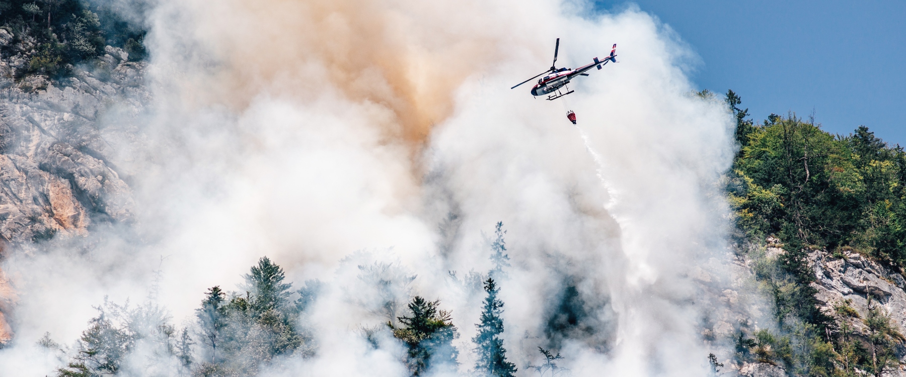 Helicopter dropping flame retardant in a forest