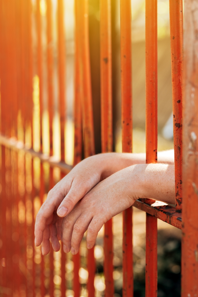 Womans hand behind prison bars