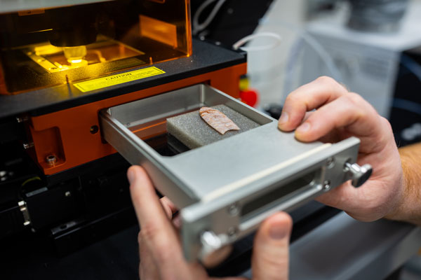 Andy Speer loads an arrowhead into ISU's mass spectrometer and laser ablation system