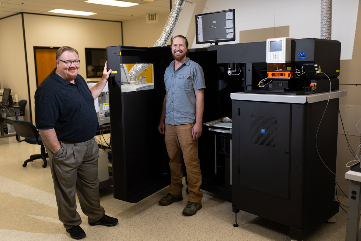 Andy Speer, left, and Christian Gattung pose for a photo beside ISU's new mass spectrometer and laser ablation system