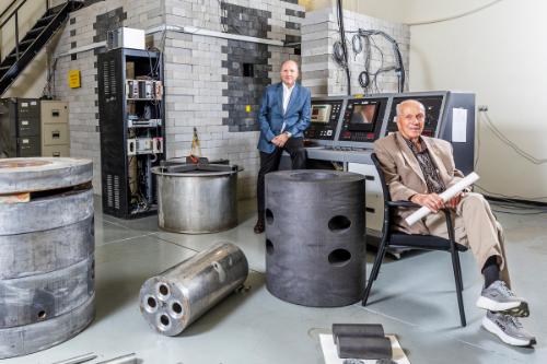 Chad Pope, professor of nuclear engineering (left), and Jay Kunze, emeritus professor of nuclear engineering (right), pose with the disassembled AGN-201 nuclear reactor on ISU’s Pocatello campus. The photo recreates a 1957 photo taken at the Aerojet Nucleonics facility in California.