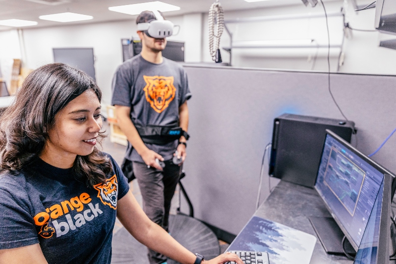 Reece Foulkrod plays Lit-VR, a virtual reality game based in 17th-century London, while Farjana Eishita, assistant professor, observes on-screen.