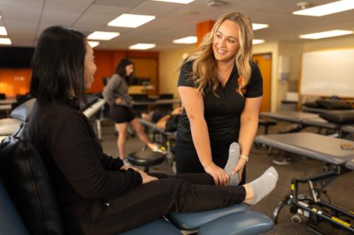 A physical therapy student performs an adjustment on a patient's ankle