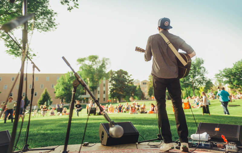 Student singing and playing guitar on quad