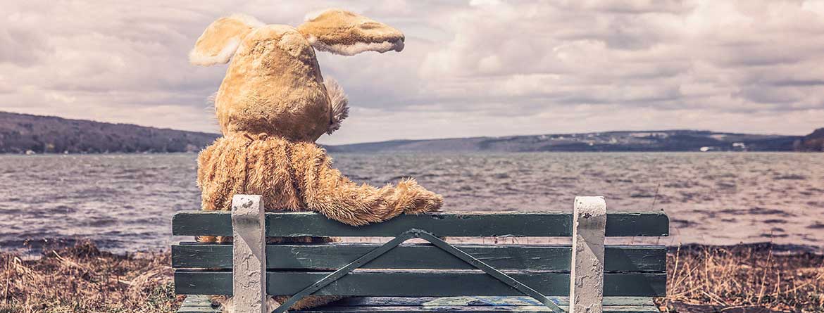 Person in bunny suit sitting on a park bench