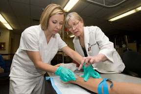 From left, College of Technology ADRN program student Valerie Parish is being advised by Dr. Linda S. Smith, program director and professor while performing an IV insertion on the simulation mannequin.