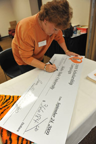 KC Felt writes ceremonial check given to ASISU President Ross Knight.