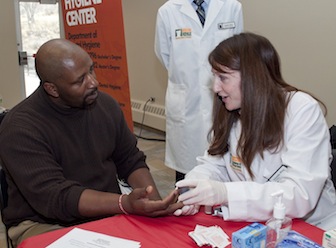 Pharmacy student Amanda Wray, right, takes the blood glucose level of Henry Evans.