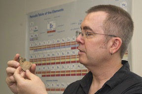 David Peterson examines a piece of ancient metal in a shard of pottery.
