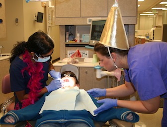 Dentist Priya Muthu (left) and dental hygienist Christa Roberts treat young patient.