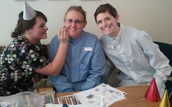 From left, senior student Amber Bowers painting on Asst. Professor Brooke Agado, leaning in the white coat is senior student Cassie Davis 